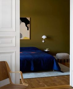 a bedroom with green walls and blue bedspread