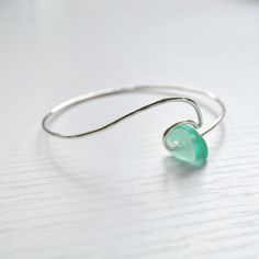 This sterling silver ocean wave bracelet is accented with cultured sea glass in beautiful hues of green. Bracelet is made with 14g sterling silver wire and hammered for a textured look. Each piece is hand formed, which adds to its unique and original quality, so please allow for slight variations. **Please also allow for variations in size and shape of sea glass** Handmade Sea Glass Bracelet As Gift, Handmade Sea Glass Bracelet For Gift, Wire Wrapped Silver Jewelry With Recycled Glass, Wire Wrapped Silver Recycled Glass Jewelry, Handmade Recycled Glass Bracelet, Hand Wrapped Green Sterling Silver Jewelry, Elegant Green Sea Glass Jewelry, Wave Bracelet, Green Bracelet