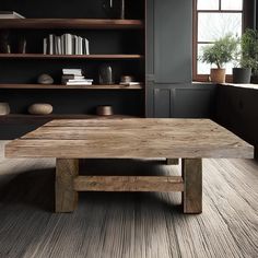 a wooden table sitting in the middle of a living room next to a book shelf