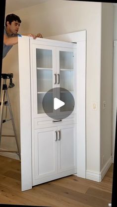 a man standing next to a tall white cabinet