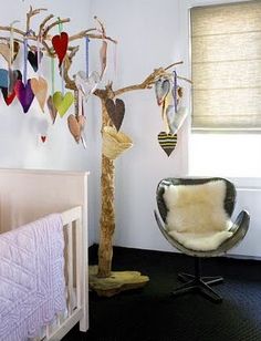 a baby's room with a crib, chair and tree