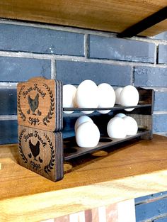 an egg rack with eggs in it on top of a wooden table next to a brick wall