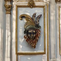 a gold and black mask mounted to the side of a building