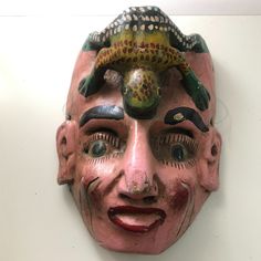 a mask that has some kind of animal on it's head and is hanging on the wall