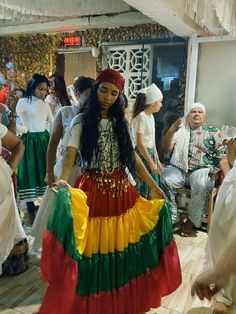 a group of people standing around each other in colorful dresses and headdresss