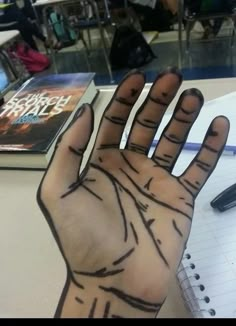 a person's hand with lines drawn on it in front of a notebook and pen