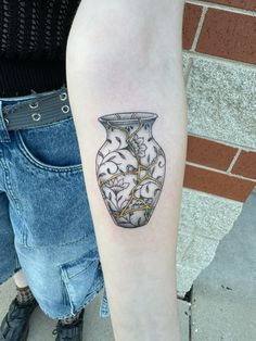 a woman with a tattoo on her arm has a vase in the shape of a heart