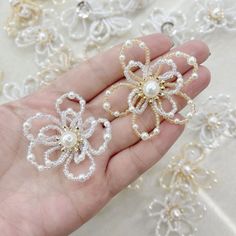 two white pearls and gold filigrees in the palm of someone's hand