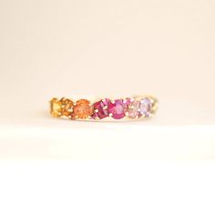 a gold ring with different colored stones on it's sides, sitting on a white surface