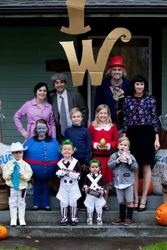 a group of people in costumes standing on the front steps of a house with pumpkins