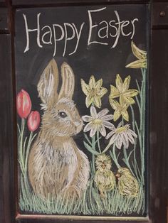 a chalk drawing of a rabbit and flowers on a blackboard with the words happy easter