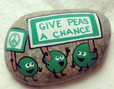 a rock painted to look like some kind of peace sign with the words give peas a chance written on it