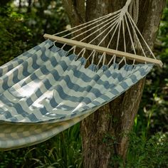 a blue and white striped hammock hanging from a tree