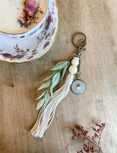 a tasseled keychain sitting next to a teacup and saucer