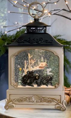 an old fashioned clock is sitting on a table in front of a christmas tree with lights