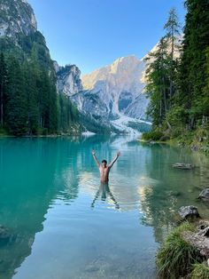 a man standing in the middle of a lake with his arms raised above his head