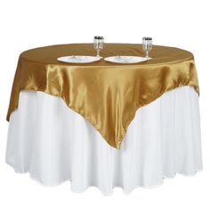 two empty glasses are sitting on top of a gold and white table cloth that has been draped over it