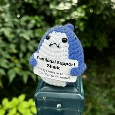 a blue and white stuffed animal on top of a parking meter with a sign that says, emotionally support shark