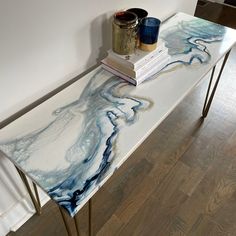 a white table with blue and gold paint on it next to a stack of books