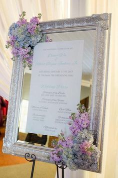 a silver frame holding a white and purple wedding program on top of a metal stand