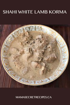 a bowl filled with meat and sauce on top of a wooden table next to a spoon