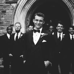 a group of men in tuxedos are standing outside an old stone church door