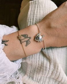 a woman wearing a white shirt and bracelet with tattoos on her arm, holding onto the wrist