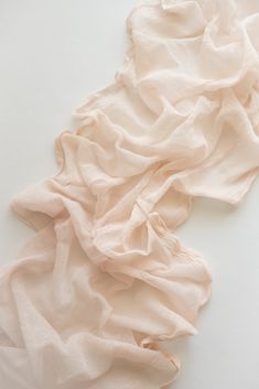 a piece of cloth is laying on top of a white surface with an object in the background