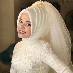 a woman wearing a white hijab smiles at the camera