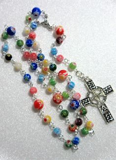 This multi colored millefiori Lutheran rosary is made with 6 and 8mm millefiori glass beads. It is rich in colors including red, blue, aqua, green, yellow, and even a black bead or 2. This rosary measures about 20 inches around and has 5 inch cross drop. I hand turned the silver plated links. The rosary parts are pewter. This rosary will be slipped into a velvet pouch and shipped in a bubble mailer. Multicolor Rosary With 8mm Beads As Gift, Colorful Beads Rosary As Gift, Multicolor 8mm Beads Rosary As Gift, Multicolor Beaded Rosary As Gift, Handmade Multicolor Rosary As A Gift, Multicolor Handmade Rosary As Gift, Handmade Multicolor Rosary As Gift, The Rosary, Bubble Mailer