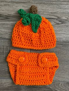 an orange crocheted hat and diaper cover on a wooden surface with buttons