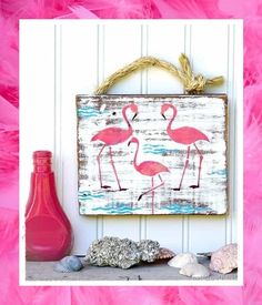 pink flamingos are hanging on the wall next to seashells and a bottle