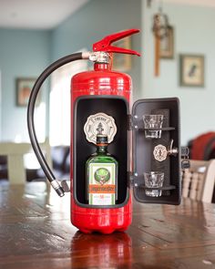 a red fire extinguisher sitting on top of a wooden table next to a shot glass