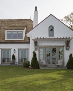 a white house with two lawn chairs in front of it