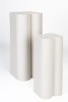 three white vases sitting next to each other on top of a table in front of a white background