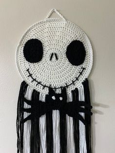 a crocheted wall hanging with a skeleton face and black bow tie on it