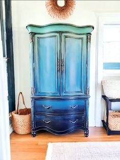 a blue armoire sitting in the corner of a room next to a basket and rug