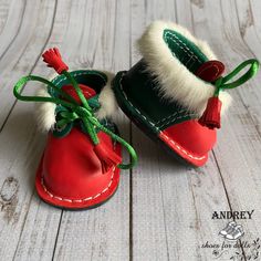 a pair of red and green baby shoes with white fur lined around the soles