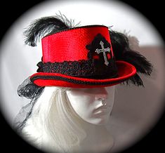 "This Gothic top hat is heavy red velvet wrapped with a black velvet and lace hatband and has a soft black crushed tulle bow & long tails in back. This Victorian style riding hat has black satin roses centered in the back.  There is a silver antiqued Celtic cross centered on a beautiful black lace applique on the front of the crown. A black lace applique rests on the back of the crown's top. The brim & crown edge are trimmed in black satin braid. This hat is loaded with black curled ostrich plumes and measures 23\".  All of the pieces you see in my shop are my original designs and carefully crafted for your pleasure... be sure to contact me for any special requests you may have! For a look at my complete Women's Hat Collection click on this link.... https://www.etsy.com/your/shops/Marcelle Gothic Fitted Brimmed Top Hat, Gothic Fitted Hat With Short Brim, Fitted Gothic Brimmed Top Hat, Gothic Top Hat With High Crown, Gothic Fitted Hats With Curved Brim, Gothic Fitted Hat With Curved Brim, Gothic High Crown Top Hat, Red Fitted Costume Hats And Headpieces For Festivals, Gothic Fitted Top Hat With High Crown