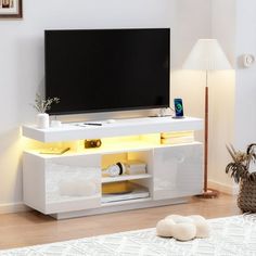 a white entertainment center with yellow lights on the bottom shelf and shelves below it, in a living room