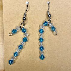 a pair of blue and clear glass beaded earrings on a piece of brown paper