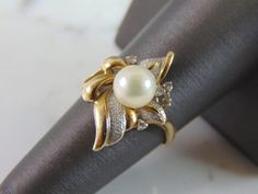 "A LOVELY, WOMENS VINTAGE 14K GOLD RING WITH WHAT APPEARS TO BE A PEARL ACCENTED WITH FIVE TINY DIAMOND CHIPS. NOT 100% SURE IF THE PEARL IS REAL OR NOT. THE DIAMONDS ARE REAL, ABOUT .05cts. THE RING IS A SIZE 7.0, AND WEIGHS 4.0g. RING IS STAMPED \"SHAW, 14K\". THIS IS A BEAUTIFUL, IMPRESSIVE GIFT FOR THAT SOMEONE SPECIAL. ANY OTHER QUESTIONS, PLEASE DON'T HESITATE TO ASK. BE SURE TO CHECK OUT SOME OF MY OTHER GREAT ITEMS UP FOR SALE. THANK YOU. IF THERE ARE ANY ISSUES PLEASE CONTACT US, WE'RE Estate Gold Ring As Gift, Estate Jewelry Stamped 14k For Wedding, Estate Diamond Jewelry For Gifts, Estate Diamond Jewelry For Gift, Estate Diamond Jewelry Gift, Estate Style Diamond Jewelry For Gift, Vintage Pearl Ring With Center Stone For Anniversary, Estate Style Gold Ring Jewelry, Estate Yellow Gold Rings For Anniversary