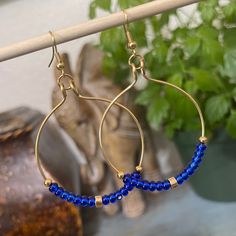 Good Tone Hoop Earrings with Royal Blue Czech Glass Seed Beads These large hoop earrings are handmade with royal blue Czech glass seed beads and gold plated beads on gold plated wire with gold plated earring wires and measure approximately 1 3/4 inches wide and 2 3/4 inches long top to bottom. * * * The last photo shows an example of the approximate size of the hoop earrings on me. These hoop earrings are perfect to wear any season and compliments Bohemian style, rustic style and vintage style o Gold Beaded Brass Hoop Earrings, Blue Beaded Metal Hoop Earrings, Beaded 14k Gold Filled Hoop Earrings, Blue Beaded Brass Earrings With Ear Wire, Blue Brass Beaded Earrings With Ear Wire, Adjustable Gold Hoop Earrings With Faceted Beads, Gold Beaded Earrings Wire Wrapped In 14k Gold Filled, Gold Beaded Earrings, Wire Wrapped, 14k Gold Filled, Gold-filled Wire Wrapped Beaded Earrings