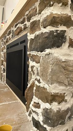 there is a fireplace built into the side of a stone wall with a door in it