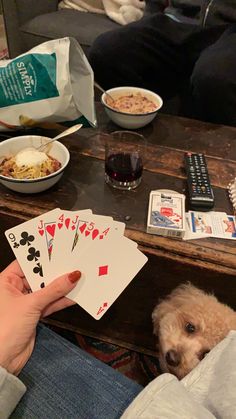 a person holding playing cards in front of a dog