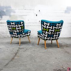 two chairs sitting next to each other in front of a white wall