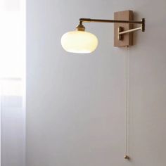 a wall mounted light on the side of a white wall next to a wooden frame