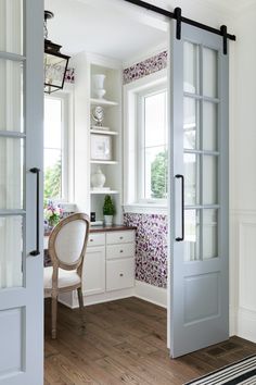 an open door leading to a kitchen with white walls and wooden flooring in the center