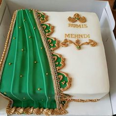 a green and white cake in a box with gold trimmings on the edges