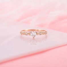 a white diamond ring sitting on top of a pink surface